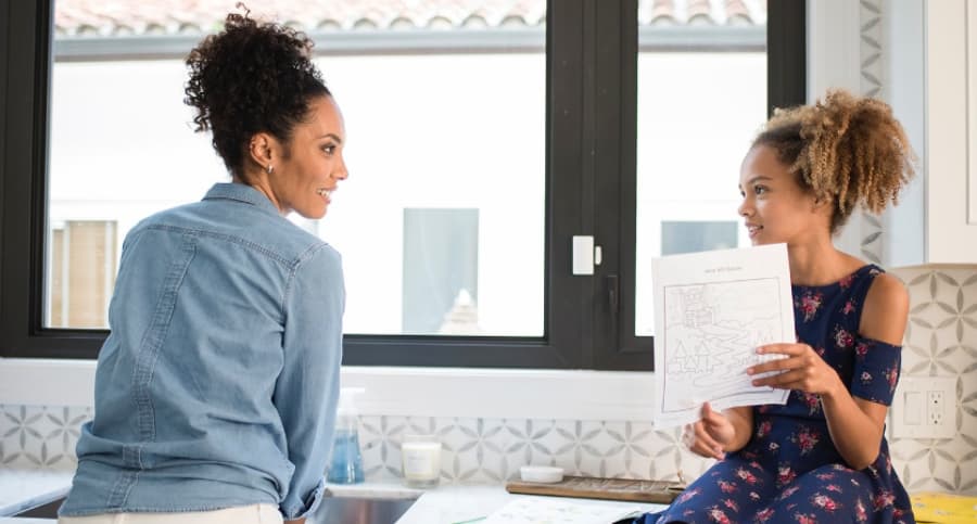 Mother and child near a kitchen window with an ADT security sensor